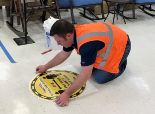 TJ applying social distancing floor decals at a Wilco store