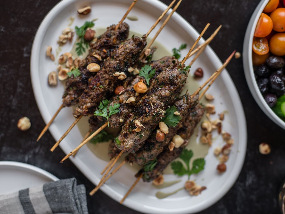 cooked hazelnut lamb kabobs on a plate with garnish