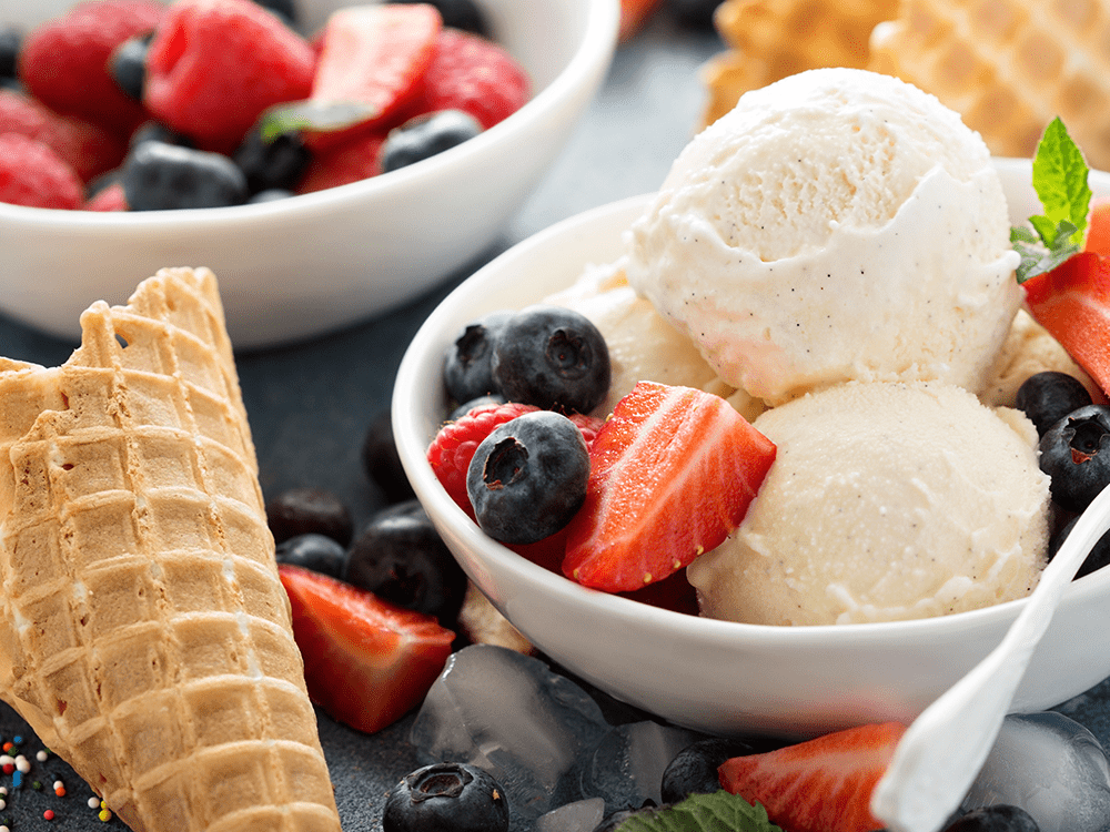 bowl of vanilla ice cream with with fresh berries on top