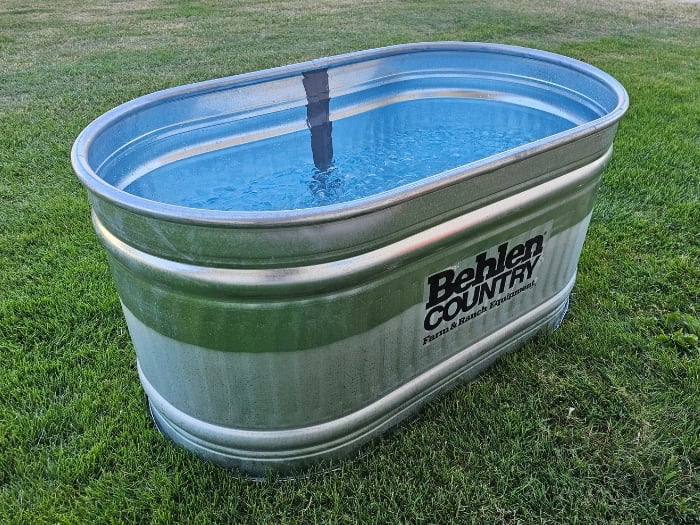 behlen country stock tank filled with ice and water on green grass