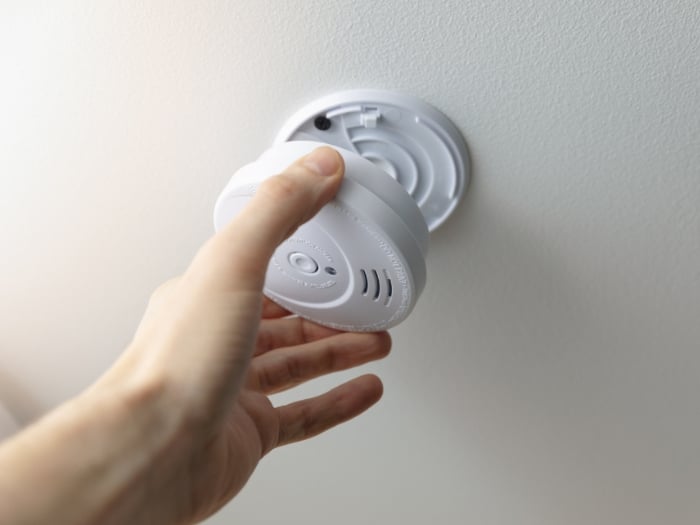 hand reaching to attach co detector on ceiling