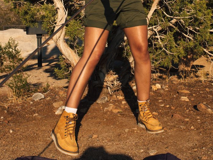 A woman in green shorts wearing brown women's work boots.