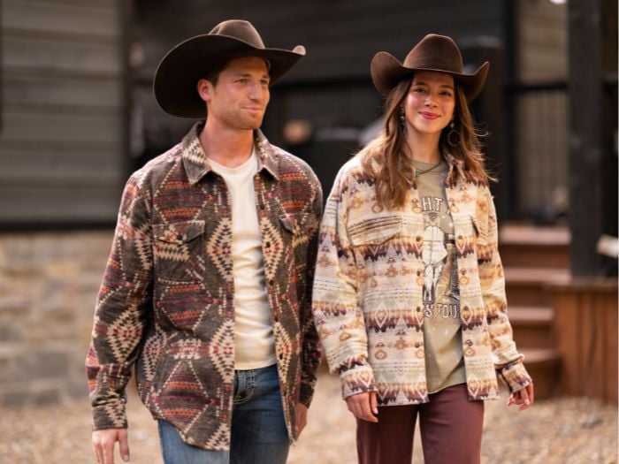 A man and a woman walking, both wearing western winter outfits from Wilco Farm Store.