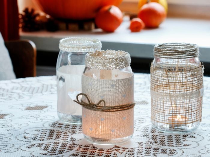 Three DIY masion jar luminaries sitting on a table.