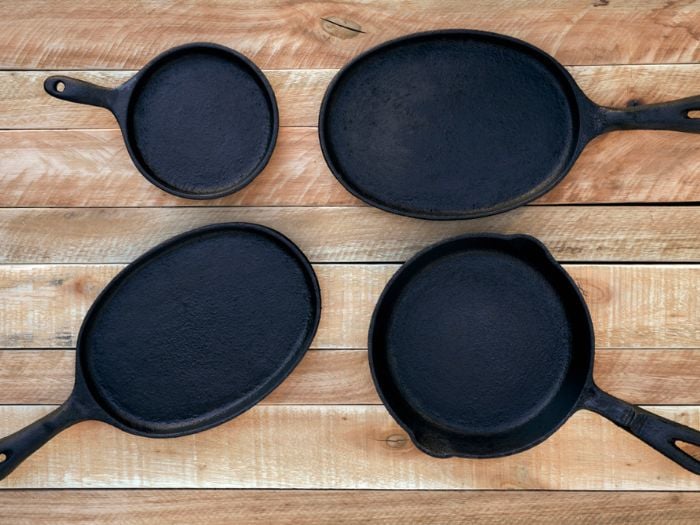 Four different size cast iron pans sitting on a wooden table.