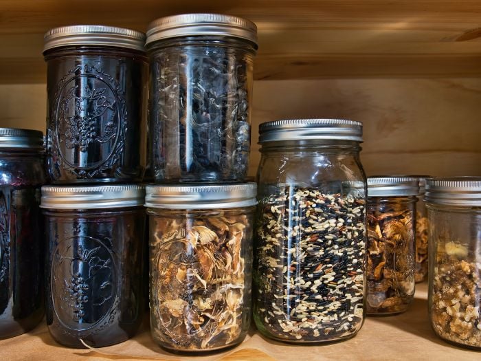 Mason jars filled with goods stacked on a pantry shelf.